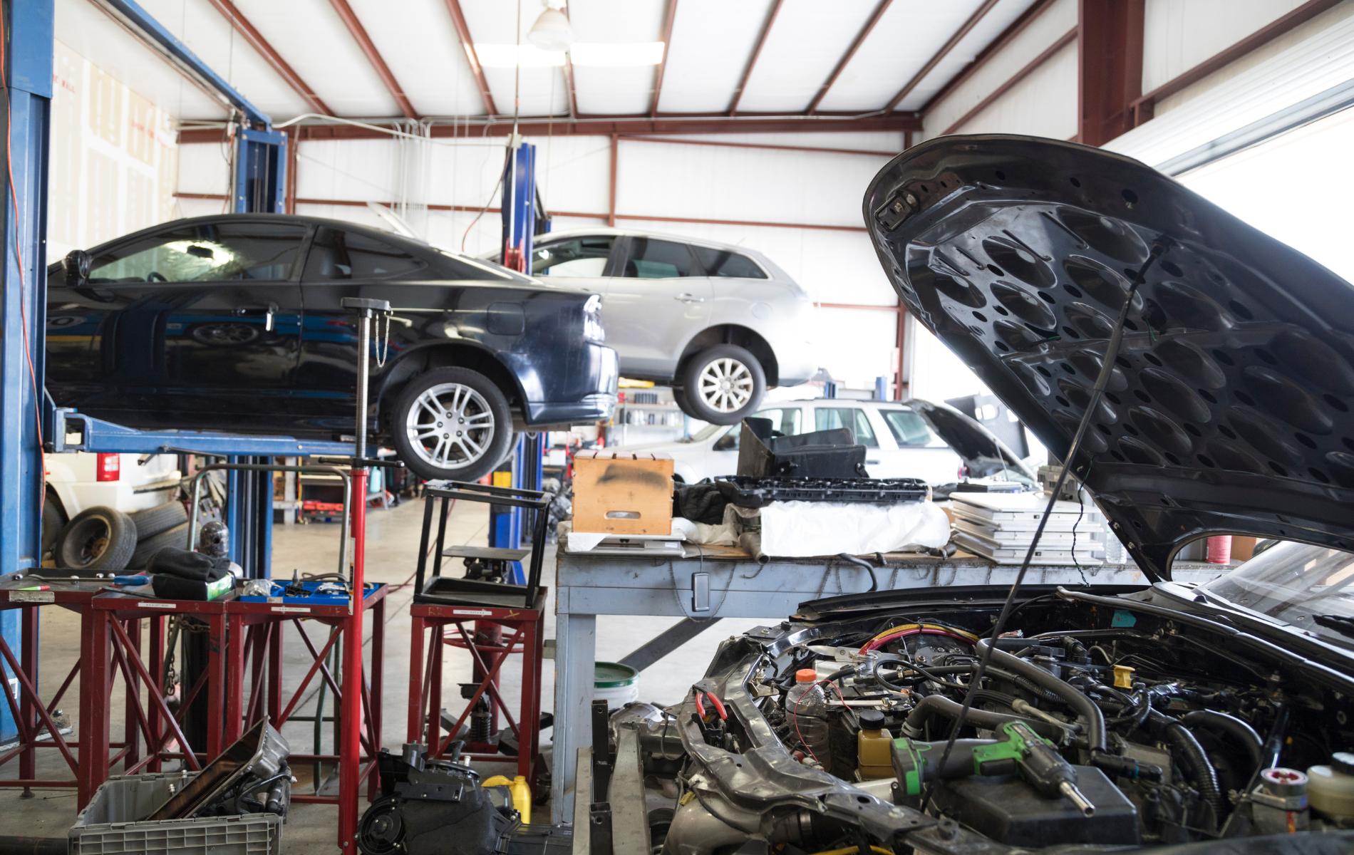 A car is being worked on in a garage with the hood open