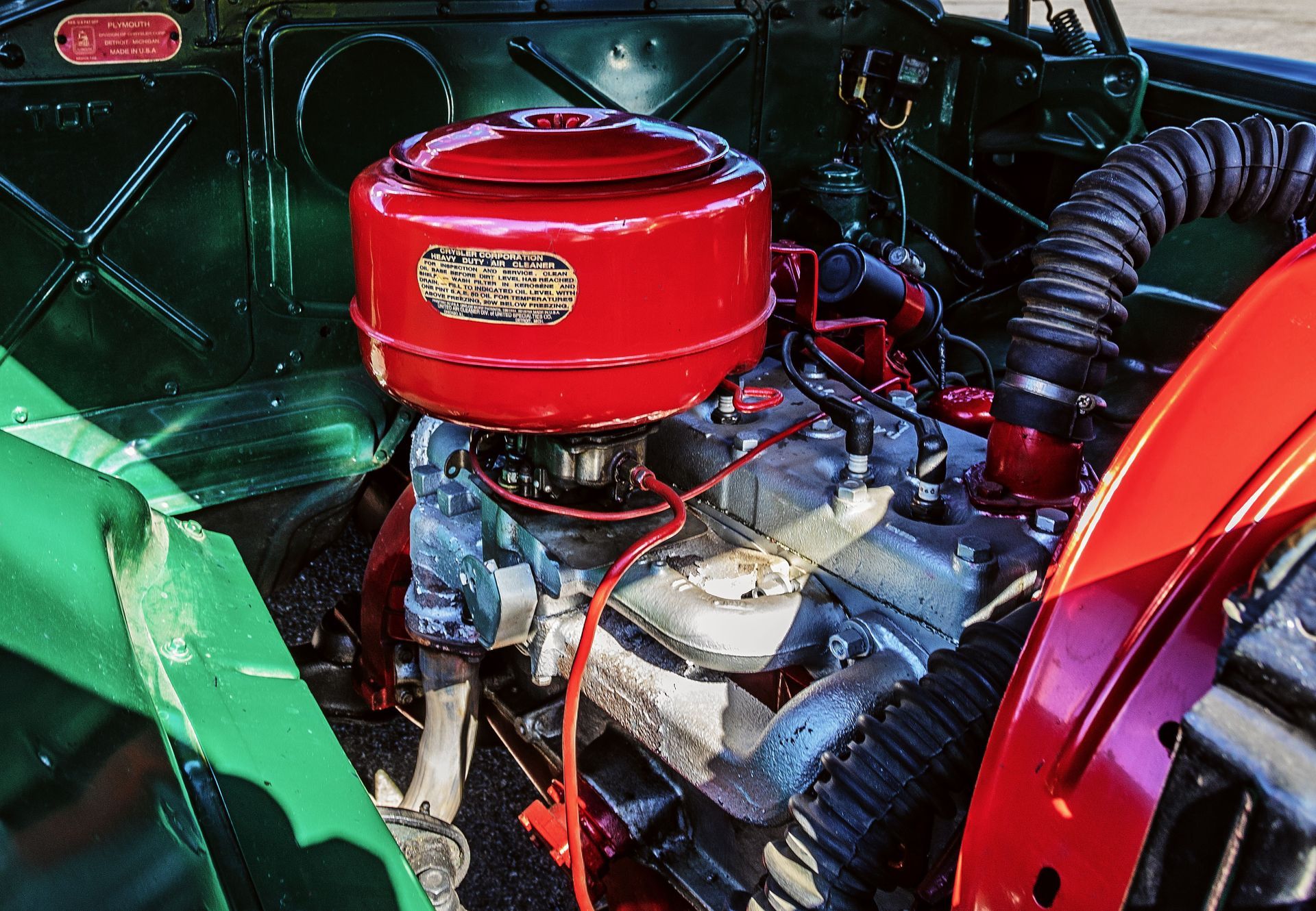 Close-up of a red engine with chrome components inside a green vehicle compartment