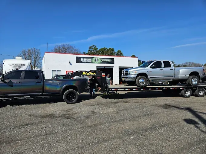 Two trucks are being towed by a flatbed trailer
