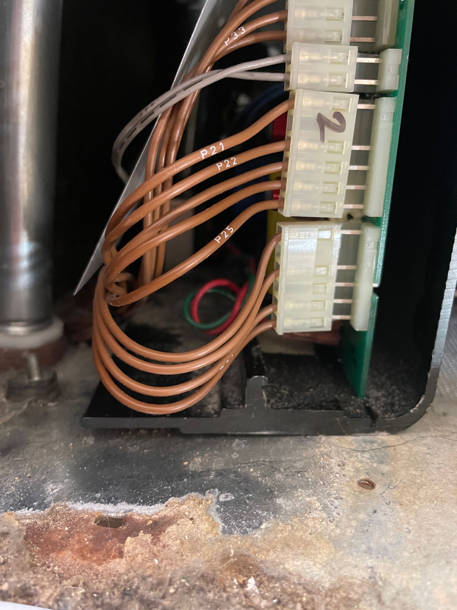 Close-up of an electrical panel with numerous copper wires connected to white connectors on a green circuit board.