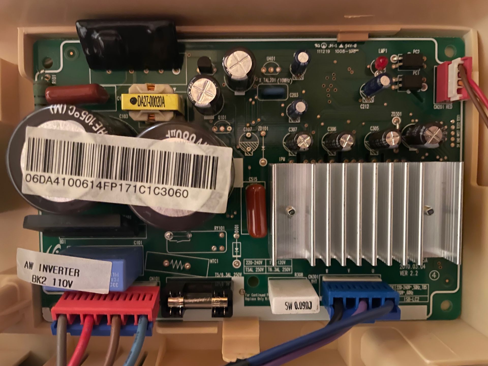 A circuit board inside a beige plastic housing. It contains capacitors, resistors, a heat sink, and several wire connectors, with labels and a barcode.