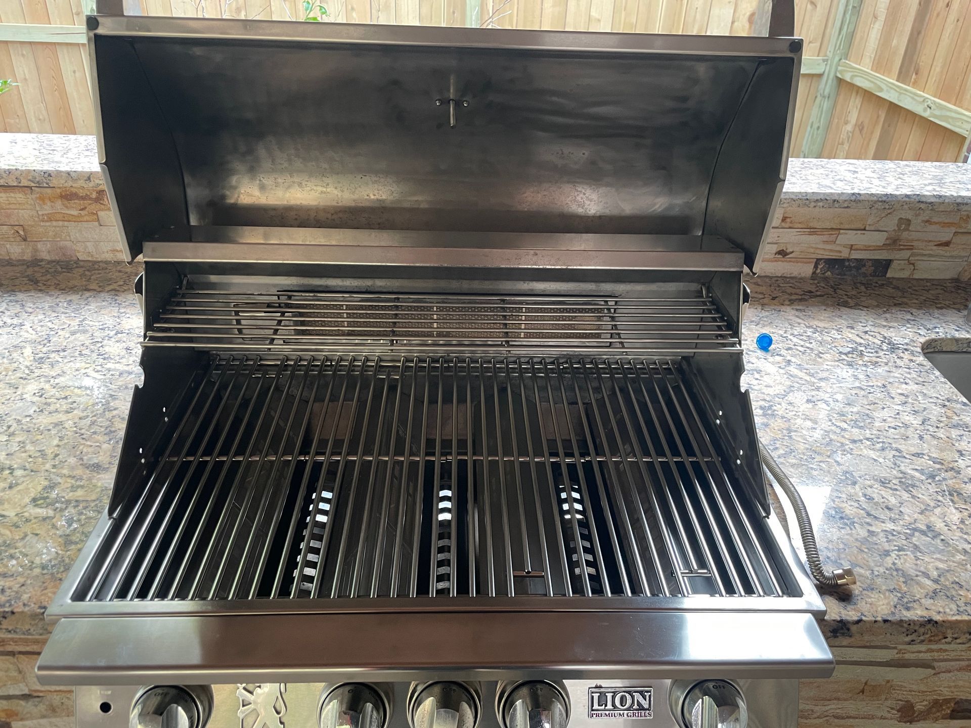 Stainless steel outdoor grill with the lid open, set into a countertop.