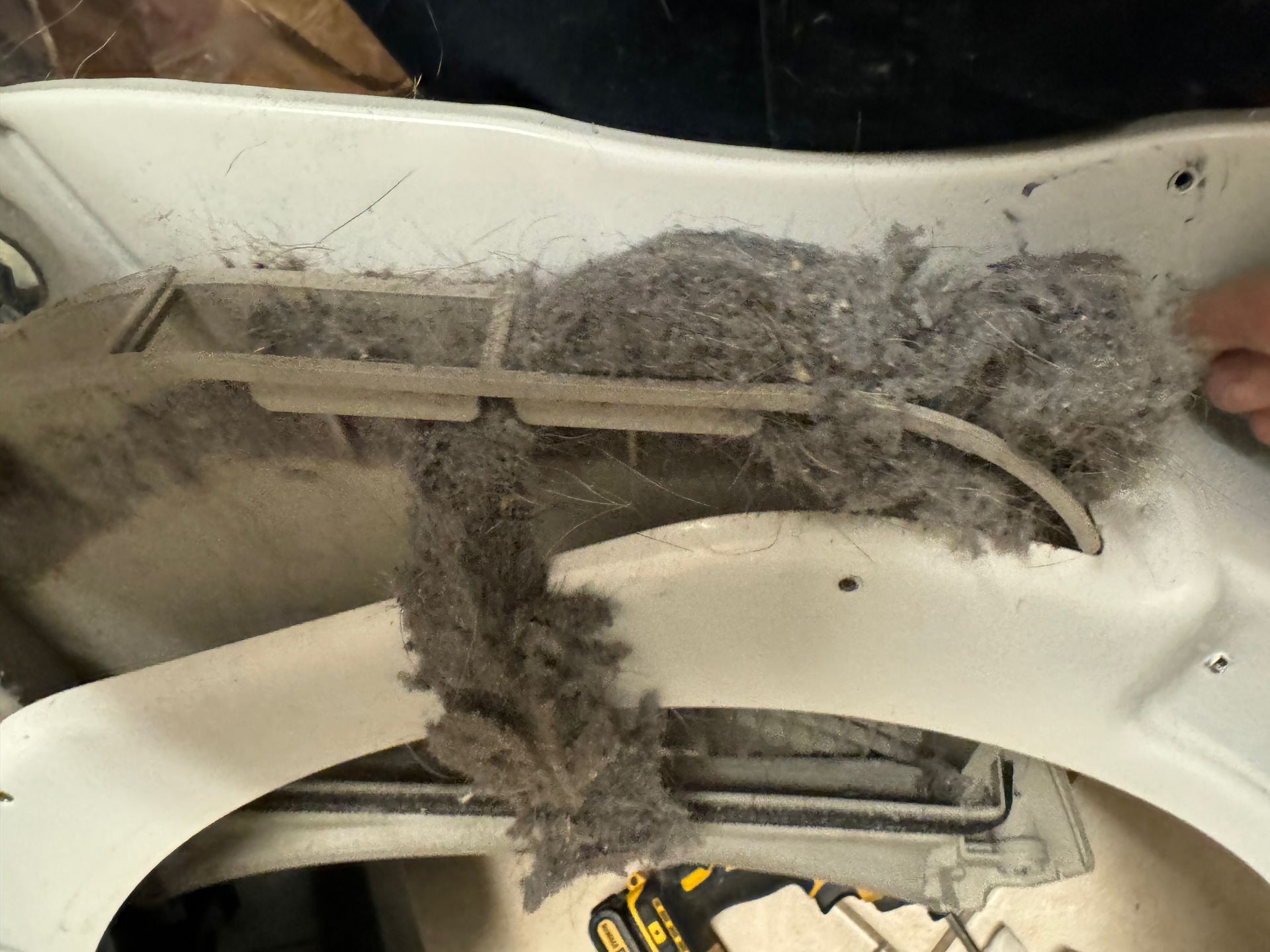Close-up of a dryer lint trap overflowing with thick, gray lint, indicating the need for cleaning.