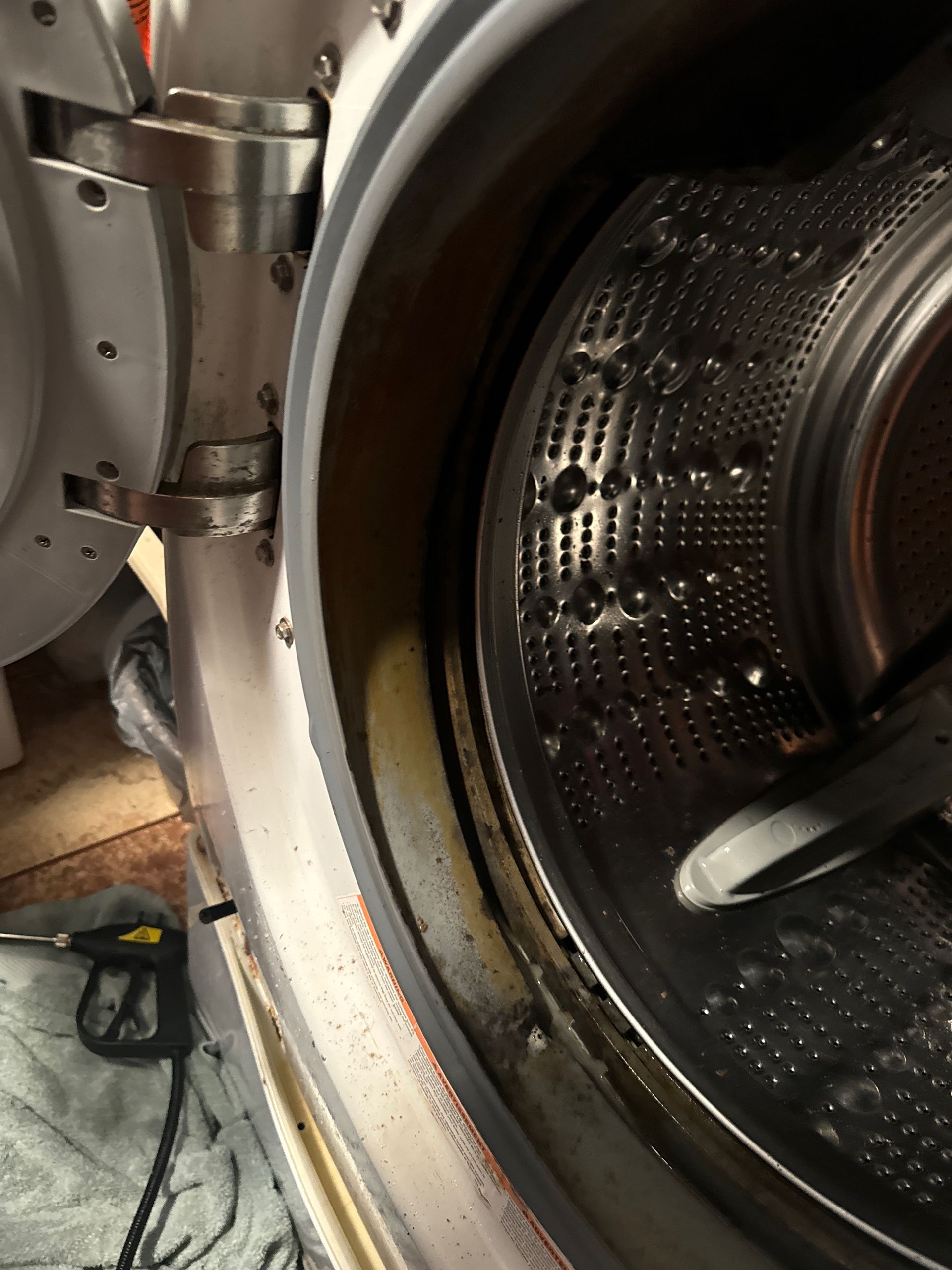 An open washing machine door, showing the interior drum and a ring of grime around the rim.