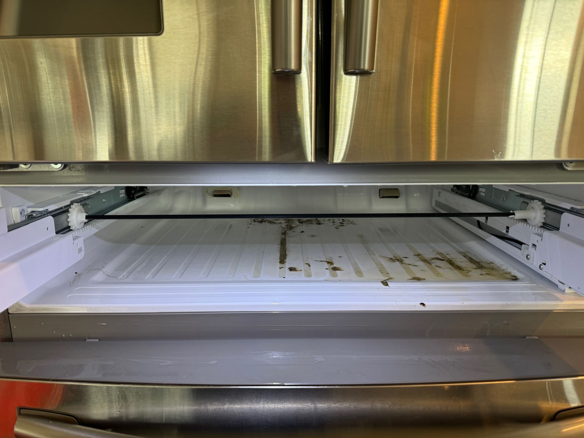 Open refrigerator drawer, stained interior, stainless steel exterior.
