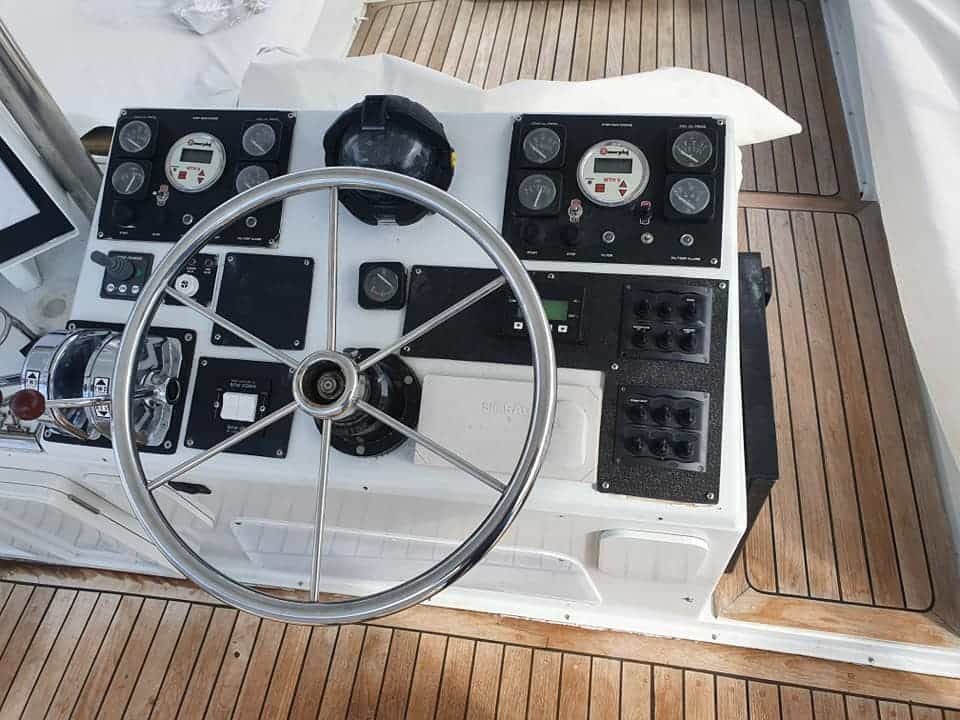 The Steering Wheel of a Boat is Sitting on a Wooden Deck — Jacko's Auto & Marine Electrics In Mackay Harbour, QLD