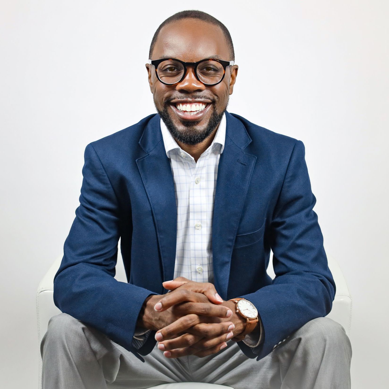 a man in a blue jacket and glasses is sitting with his hands folded and smiling. corey holman, top business leader in albany, georgia, Albany's Top Community and Business Leader