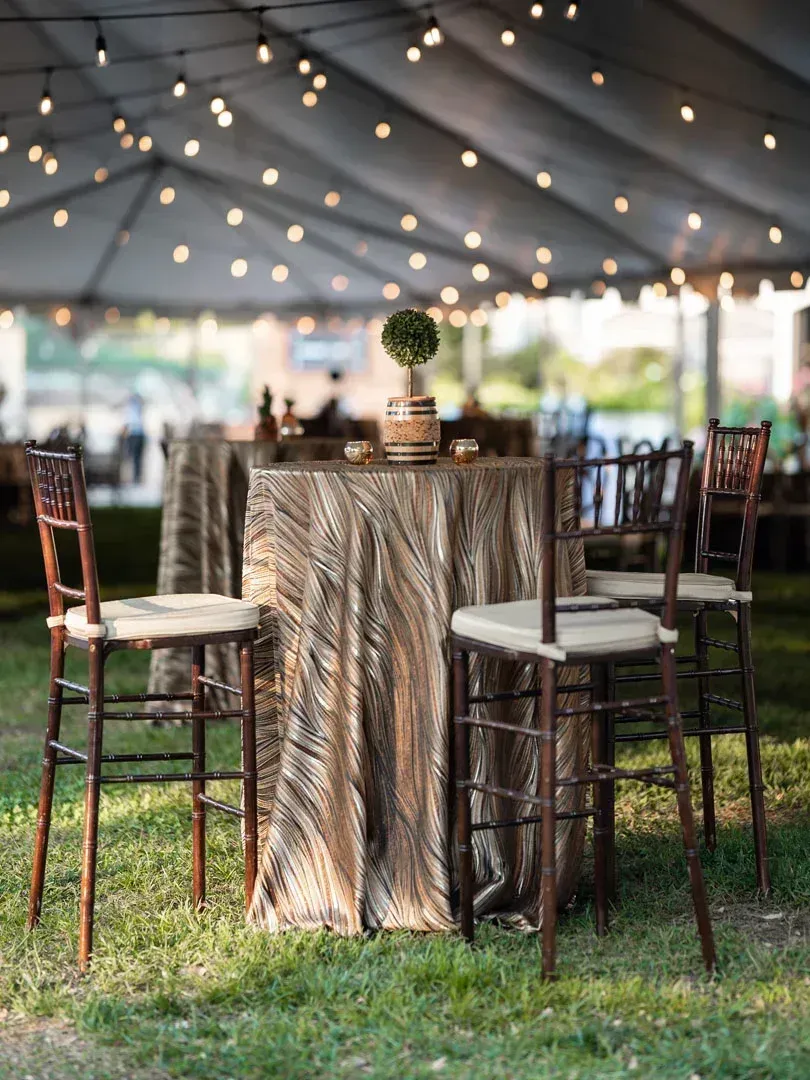 A tent with tables and chairs underneath it in the grass.