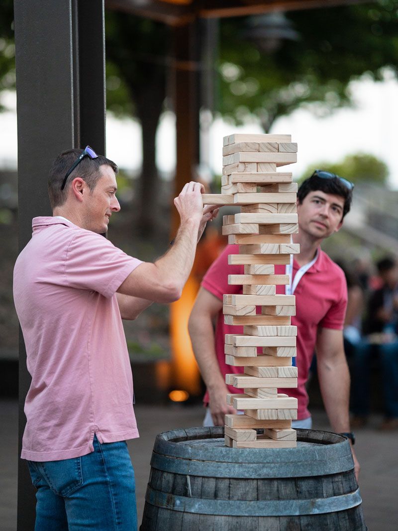 Two men are playing a game of jenga on a barrel.