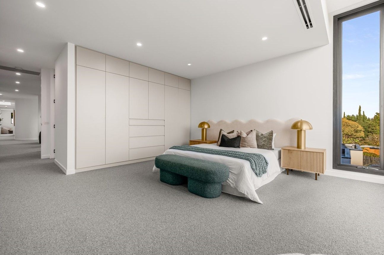 Modern bedroom with white walls, neutral carpet, king bed, and large window with a view.