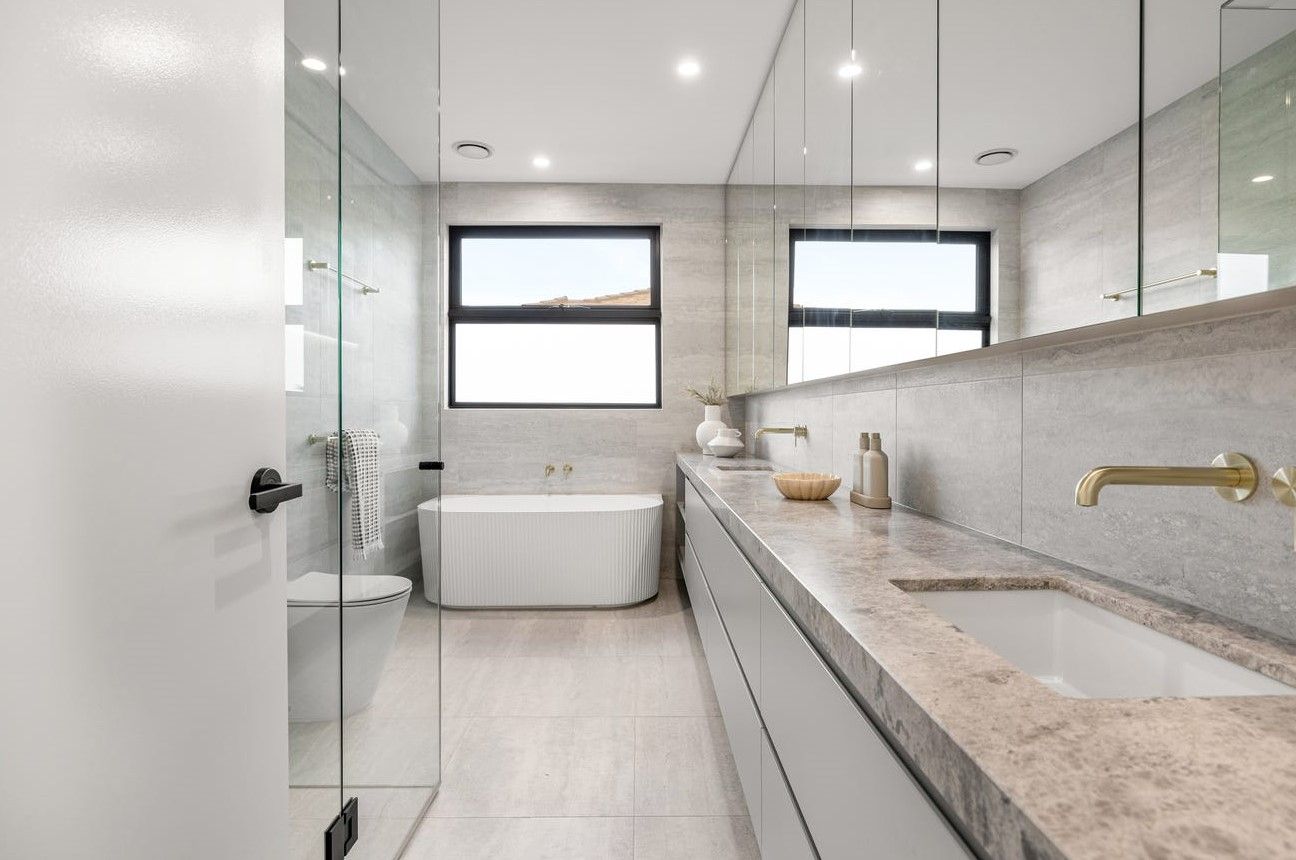 Modern bathroom with a white tub, floating vanity, and large mirror.
