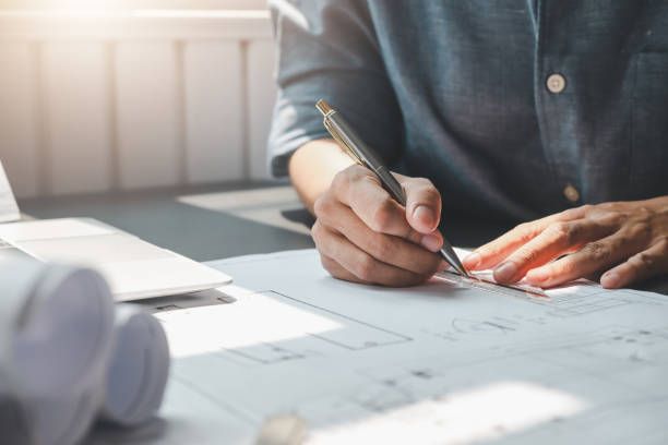 Close-up of male architect’s doing an architectural drafting by hand of a building construction.