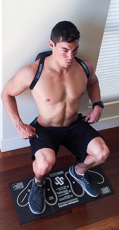 Shows a shirtless man using a SmithShaper ASR PRO and doing a SmithShaper power squat exercise as he uses a SmithShaper Squat Mat under his feet to better target his leg muscles