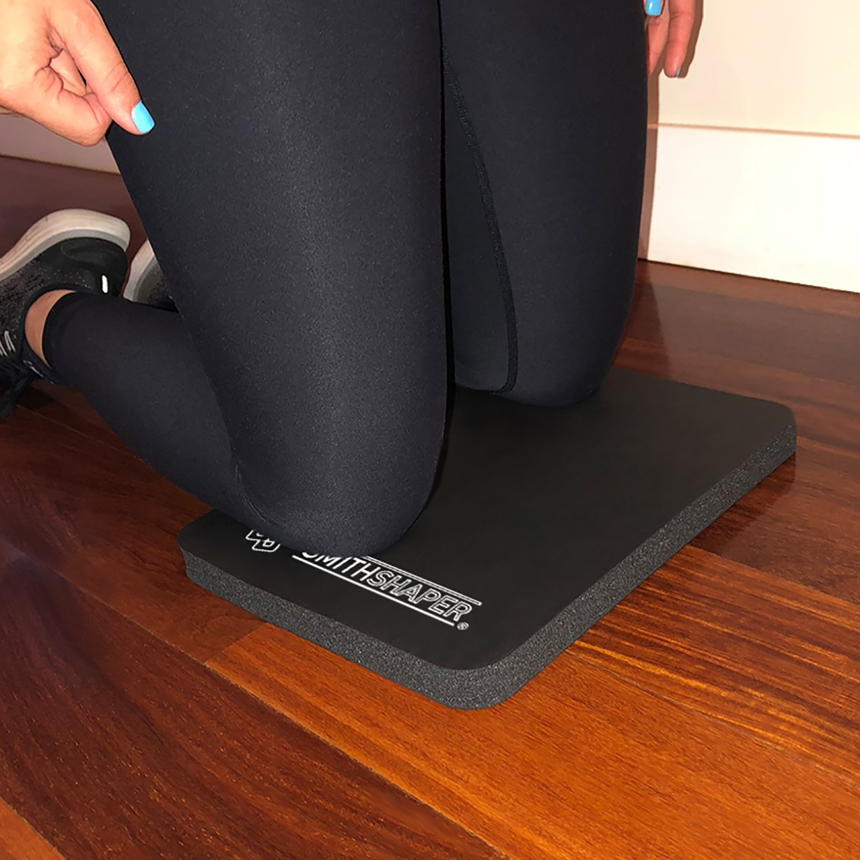 a person kneeling on a SmithShaper Super Pad with the SmithShaper logo partially showing