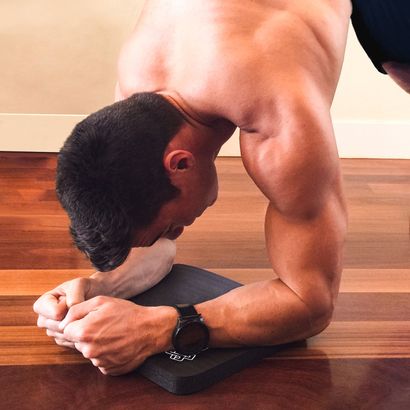 a man wearing a watch is doing a SmithShaper pike plank on a SmithShaper Super Pad workout mat for comforting knees, elbows and other body parts during exercise.