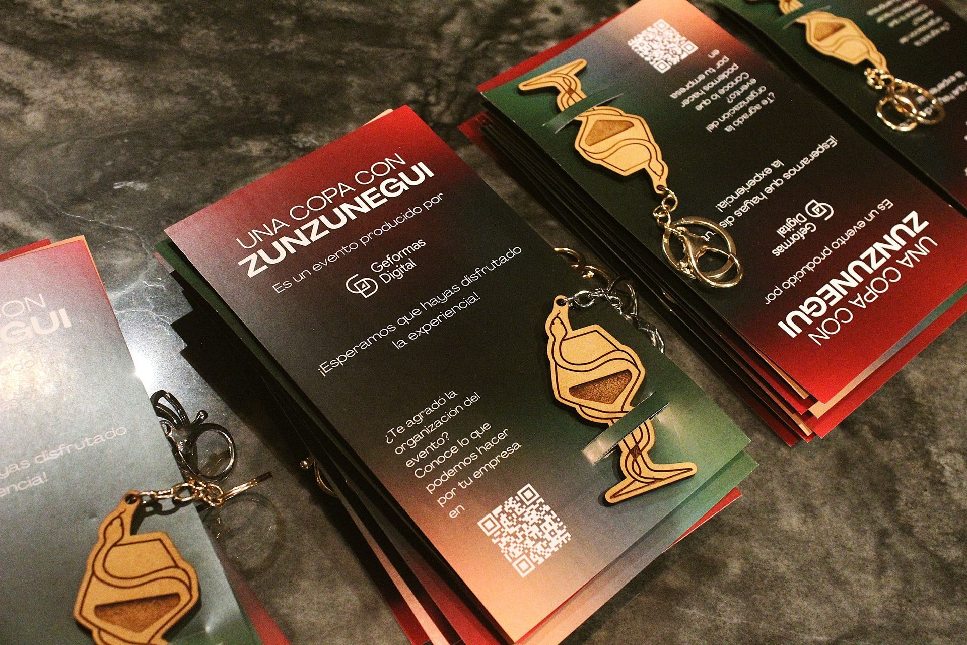 Pilas de folletos con un llavero de madera. El folleto tiene un degradado rojo y verde con la palabra 