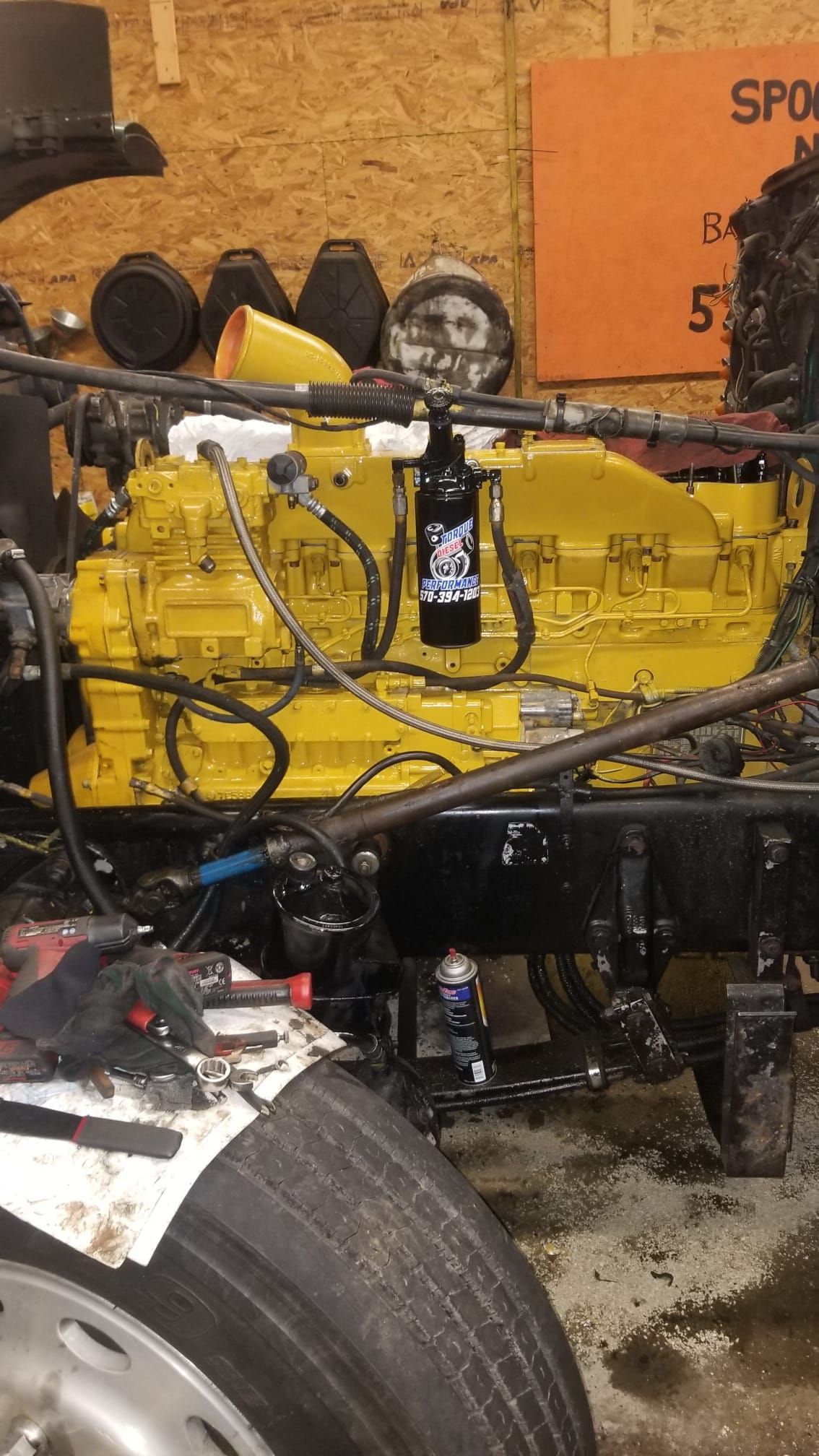 Black painted truck chassis on jack stands inside a shop.