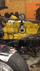 Black painted truck chassis on jack stands inside a shop.