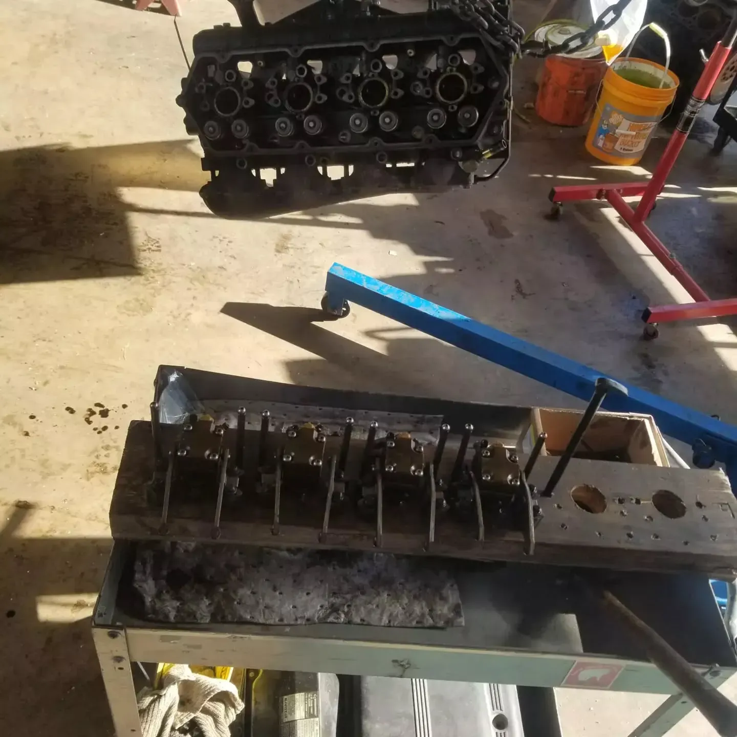 An engine block is being worked on with parts on a workbench in a garage.