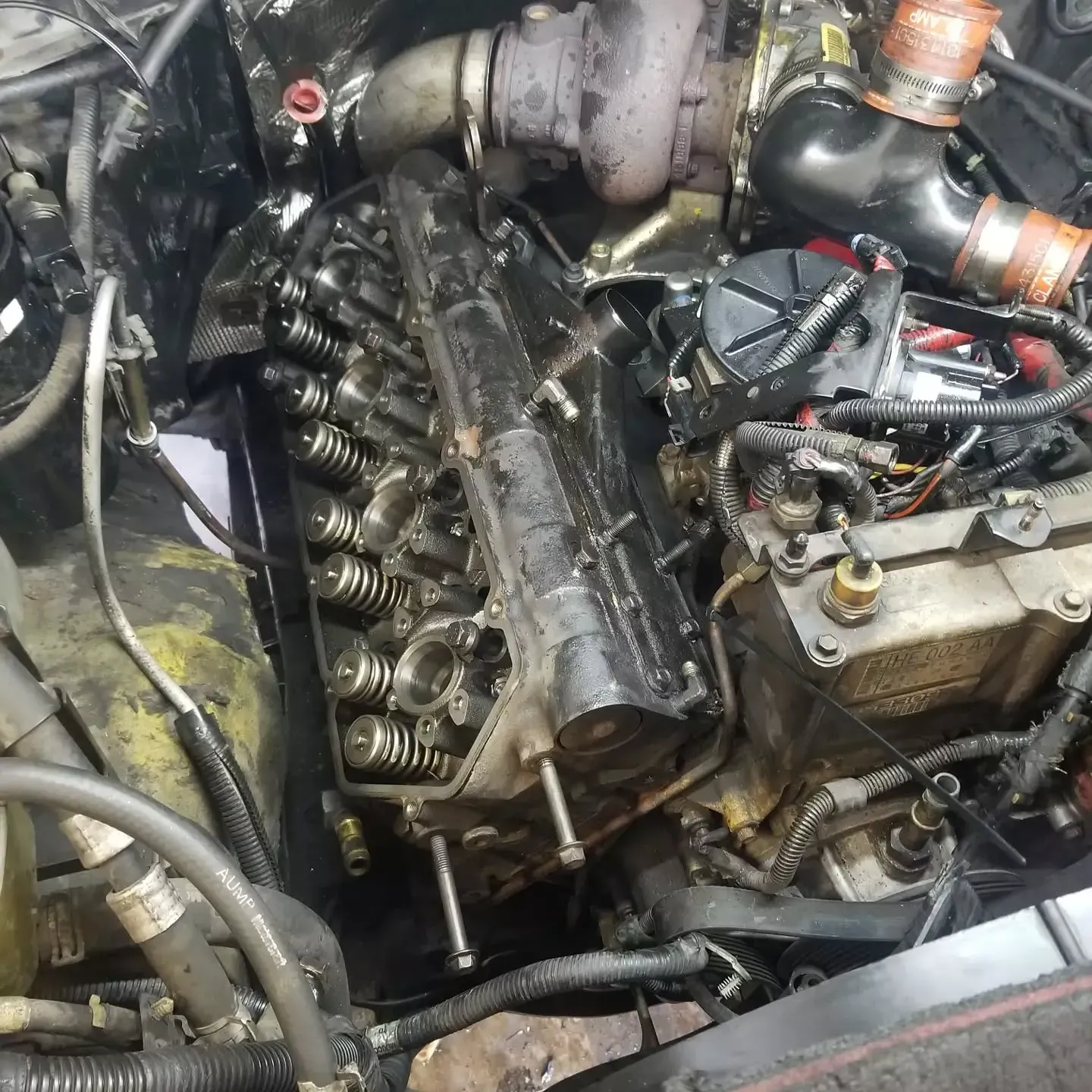 Engine with a removed cylinder head; black, rusty, and oil-stained; repair in progress.