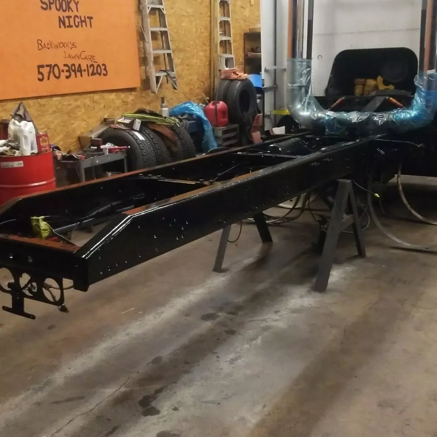 Black truck chassis on sawhorses inside a garage, ready for restoration.