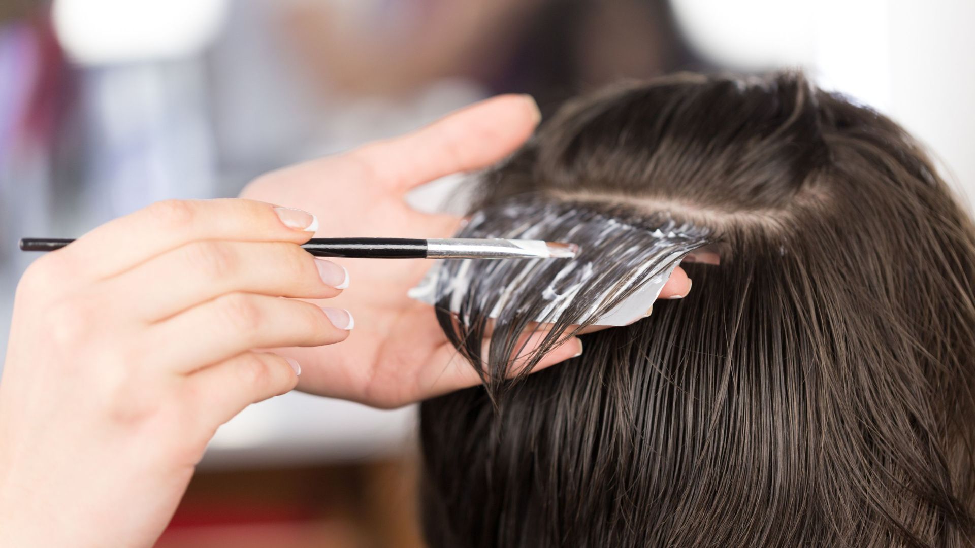 A woman is getting her hair dyed by a hairdresser.