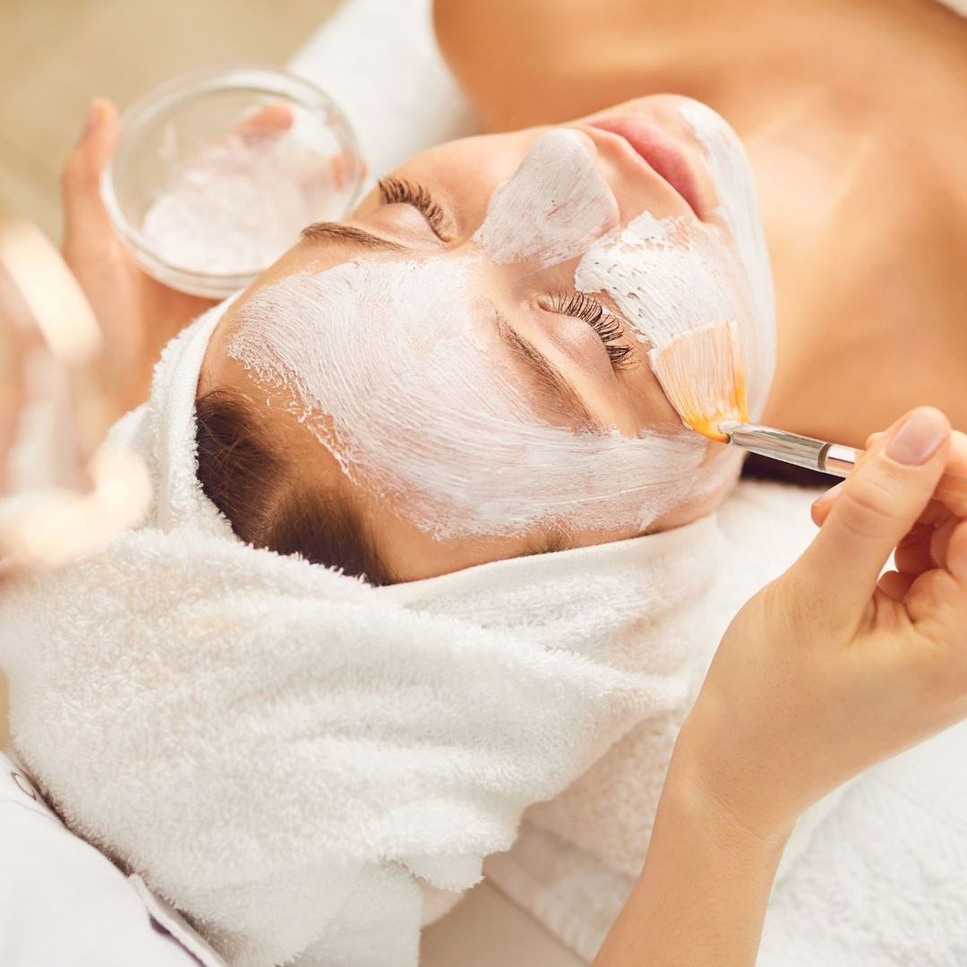 A woman with a towel wrapped around her head is getting a facial treatment.