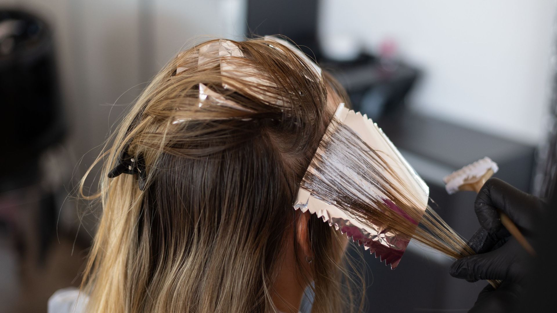 A woman is getting her hair dyed in a salon.