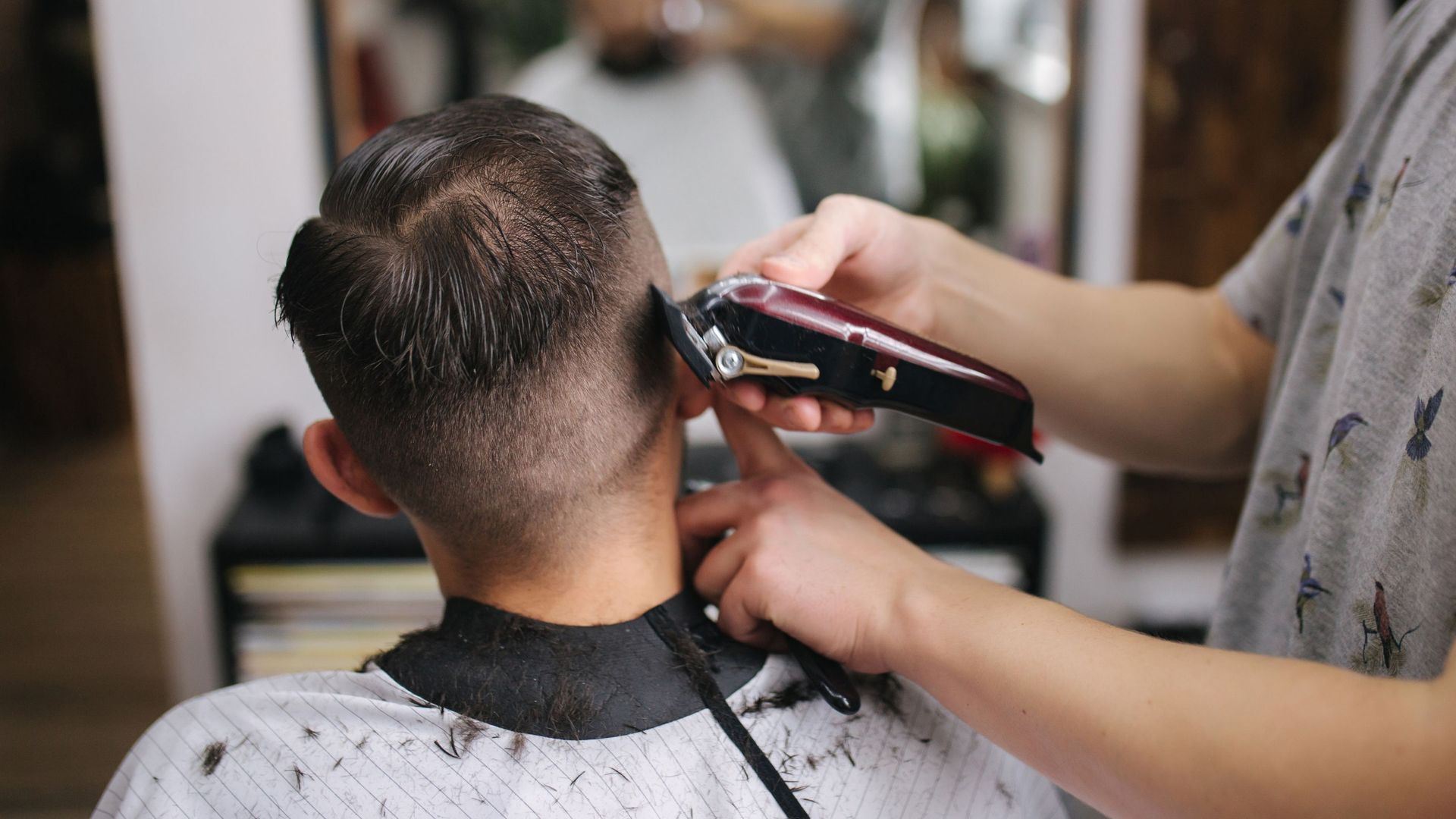 A man is getting his hair cut by a barber in a barber shop.