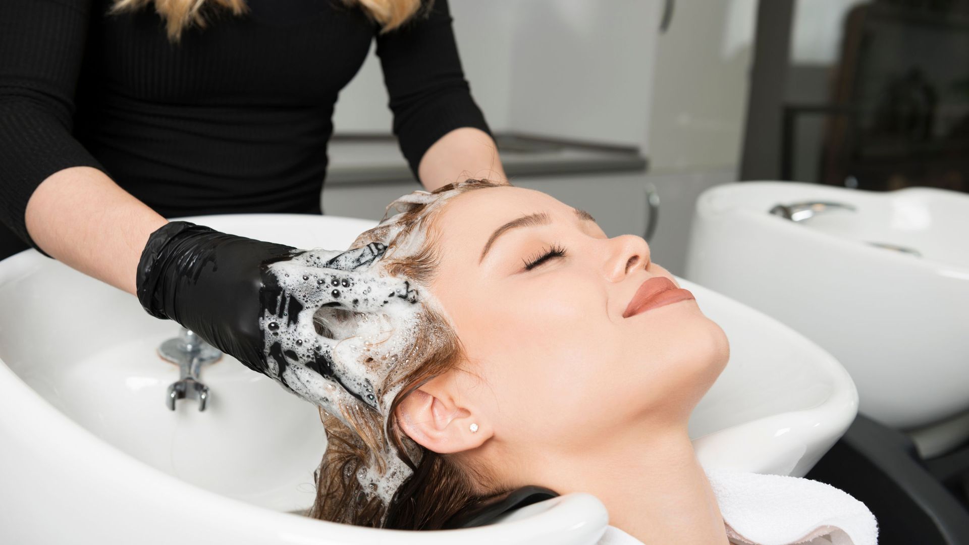A woman is getting her hair washed at a salon.