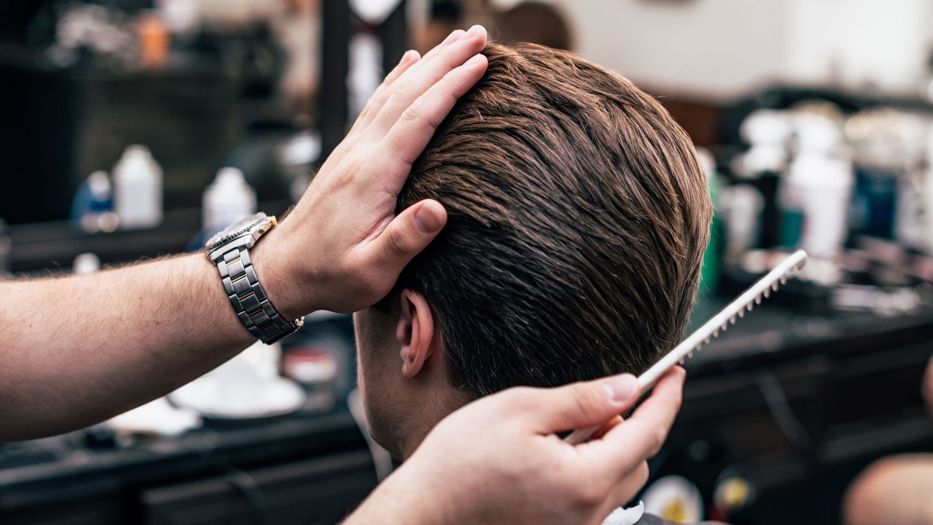 A man is getting his hair cut by a barber in a barber shop.