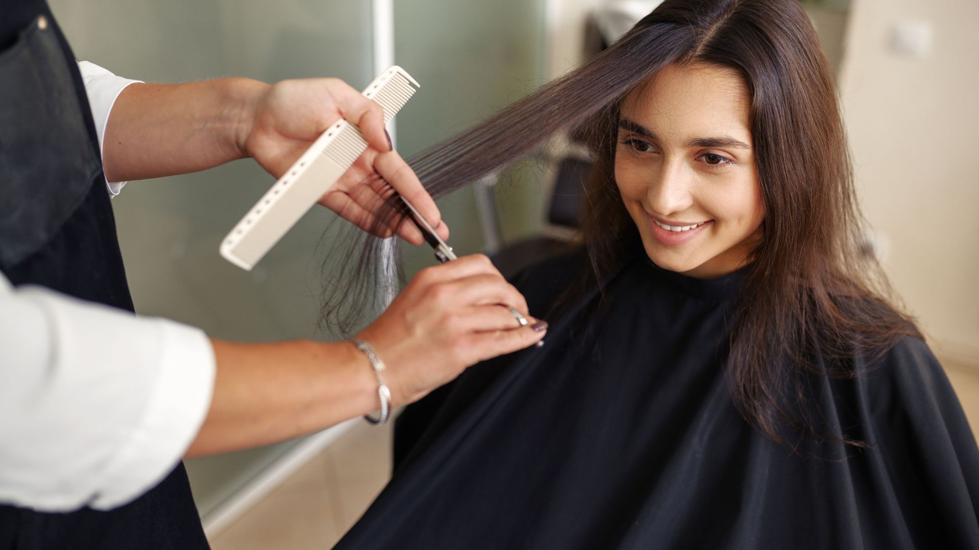 A woman is getting her hair cut by a hairdresser in a salon.