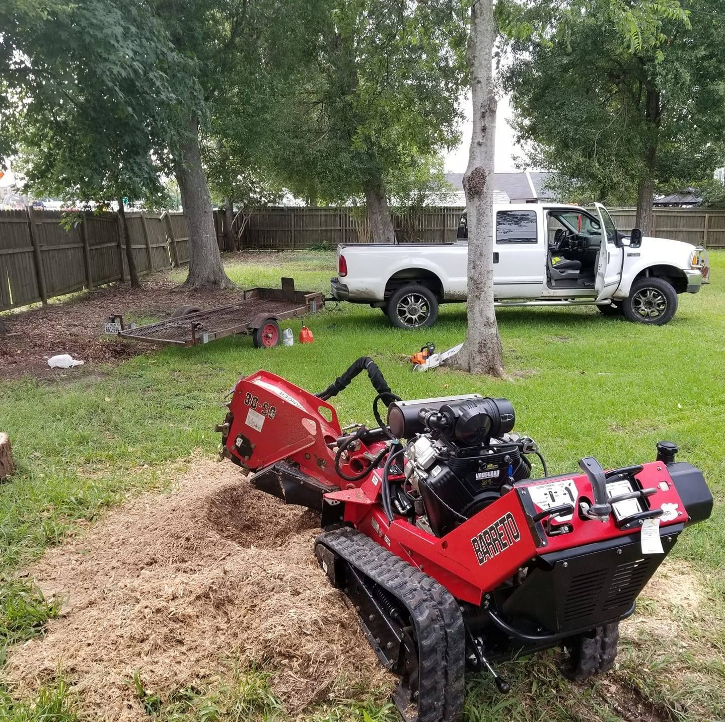 Wood chipper disposing of tree debris into the back of a high sided trailer after a successful tree removal in Beaumont, TX