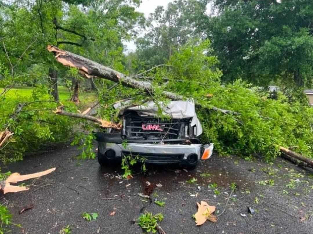 Tractor with bucket attachment sitting near a pile of tree debris ready for removal from clients property in Southeast Texas