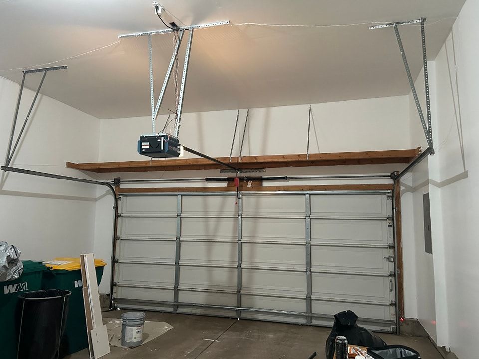 Garage with closed white door, automatic opener, and metal support beams.