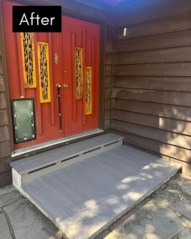Red front door with gray steps after renovation.