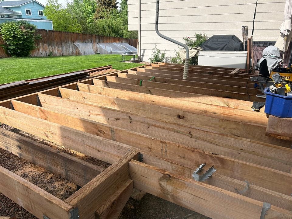 Wooden deck frame being built in a backyard.