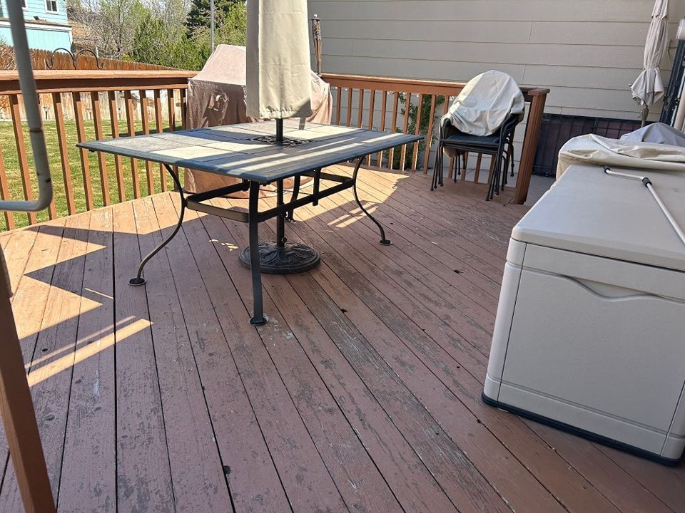 Wooden deck with a table, umbrella, storage bin, and chair.