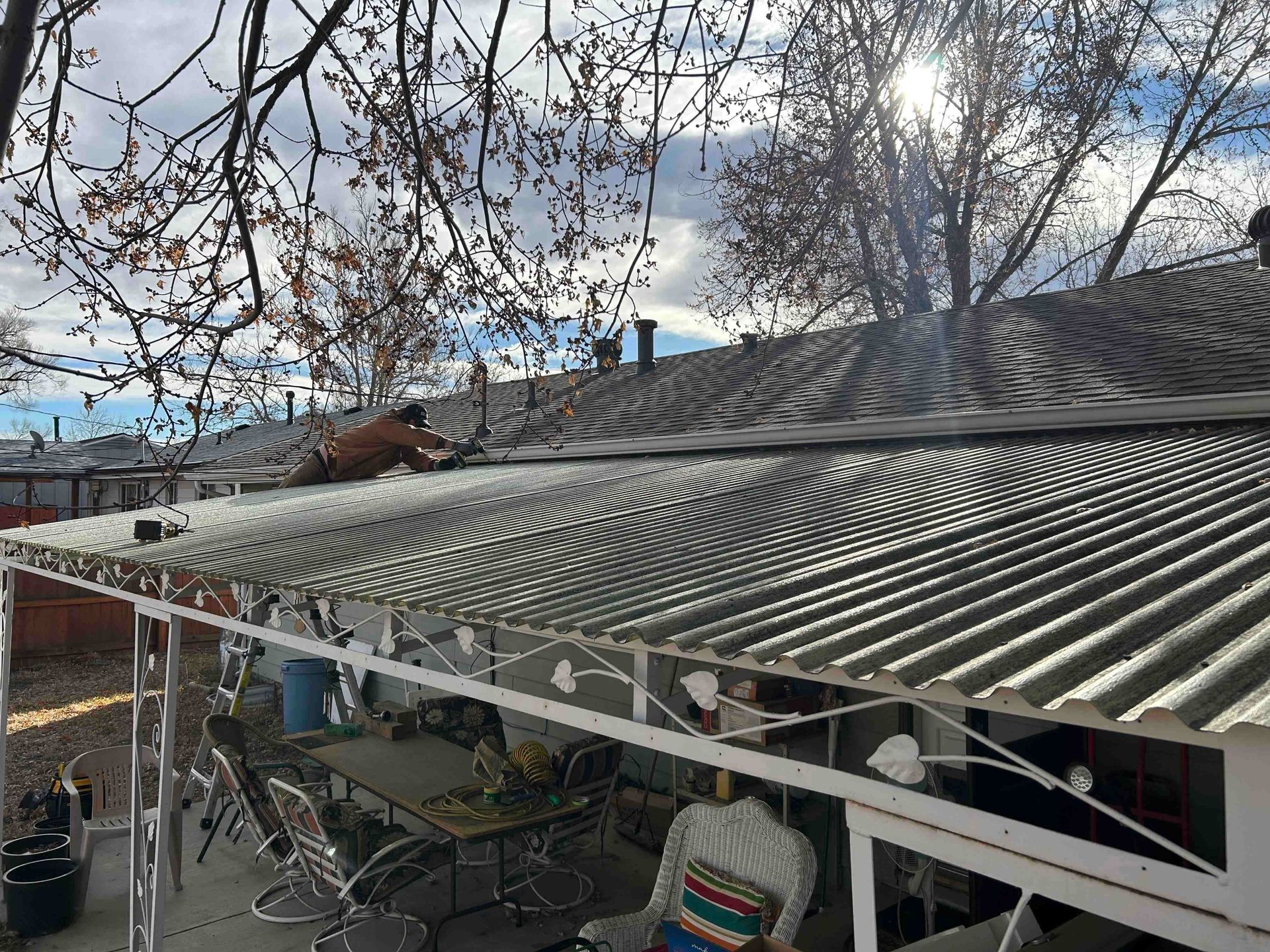 Person working on a corrugated metal roof, part of a patio cover, sunny day.