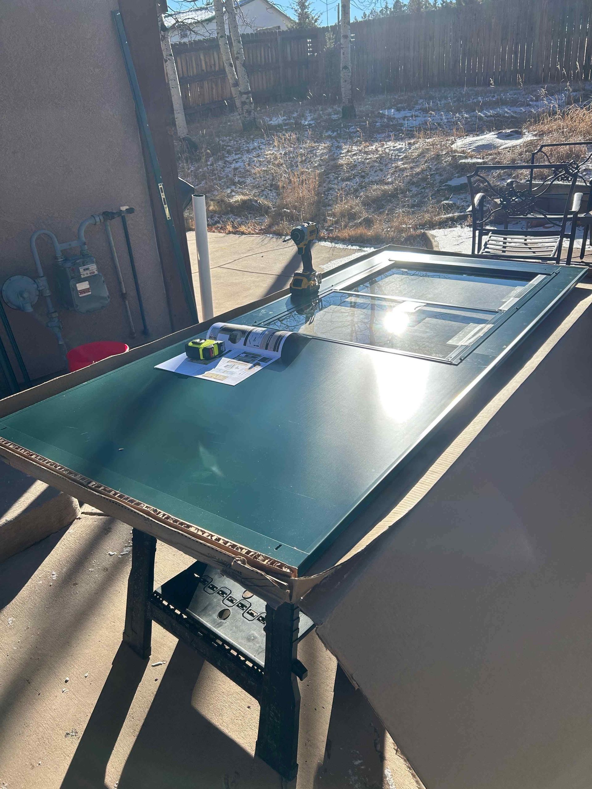 A backyard with a wood fence, mulch area, grass, and a few small rocks lining the perimeter.