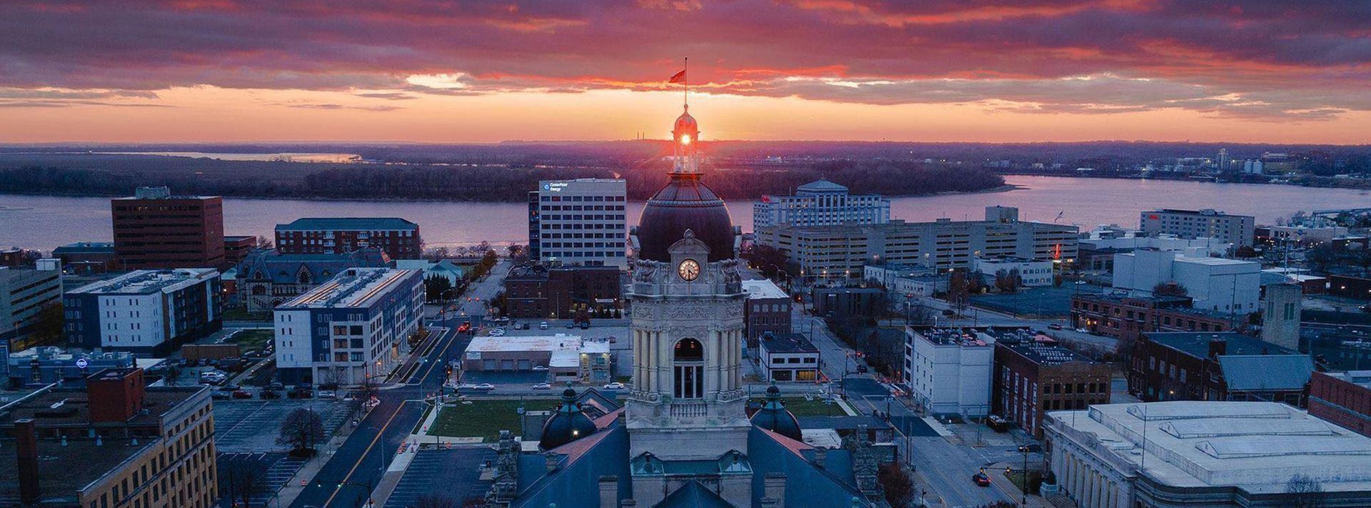 An aerial view of a city at sunset with a clock tower in the foreground.