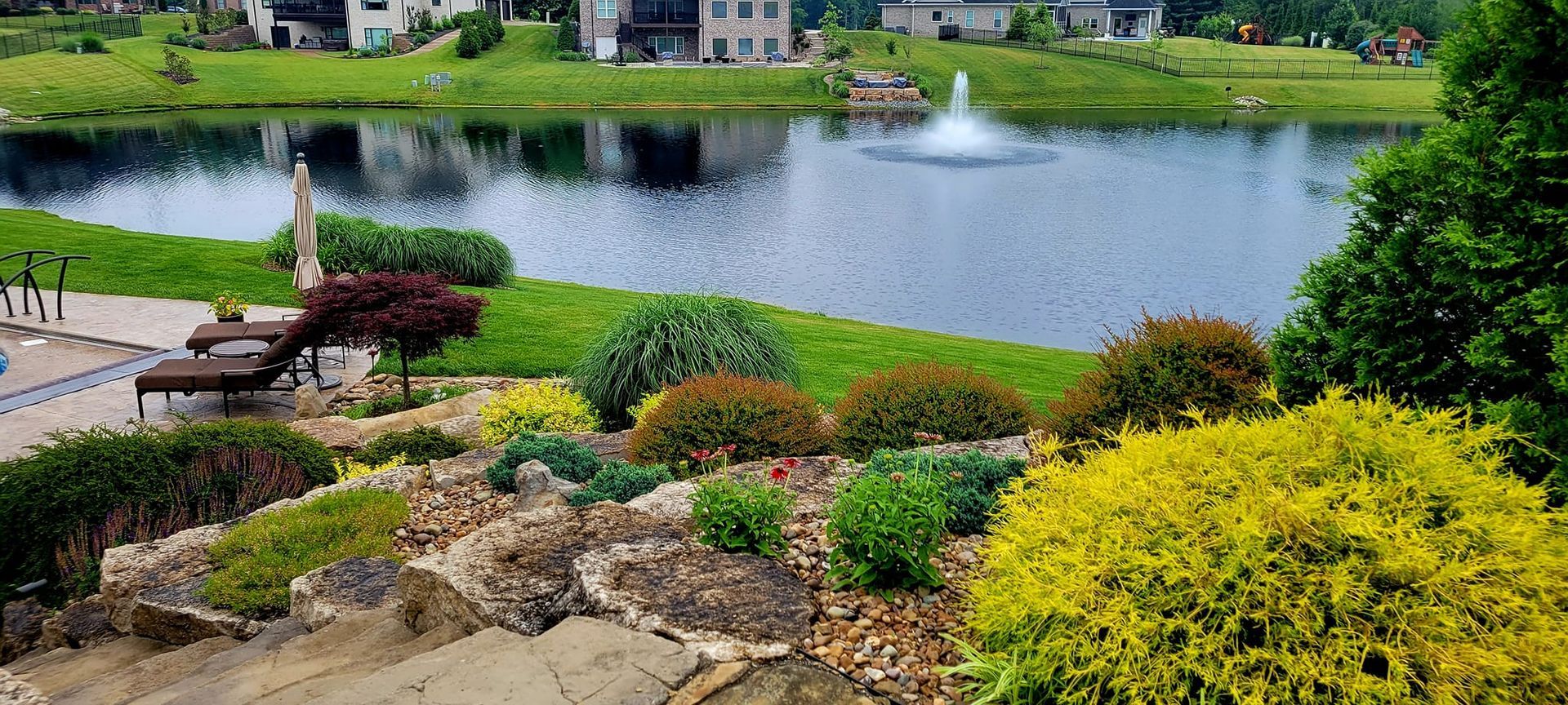 There is a fountain in the middle of the pond in the backyard.