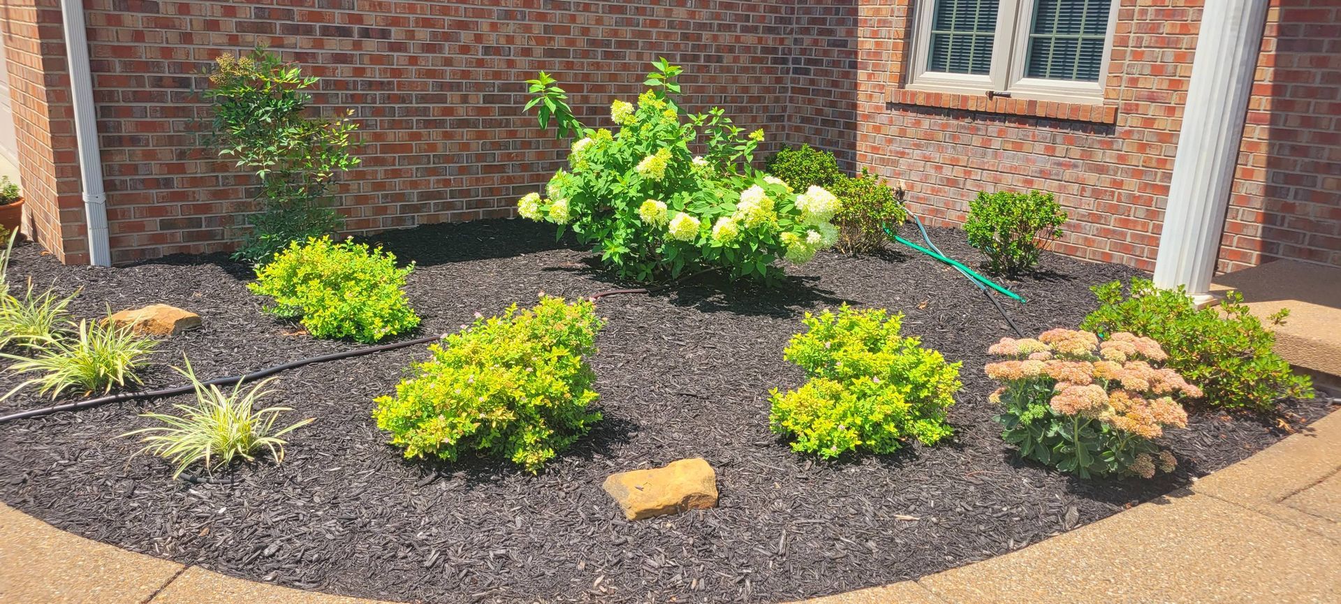 A brick house with a circular garden in front of it.