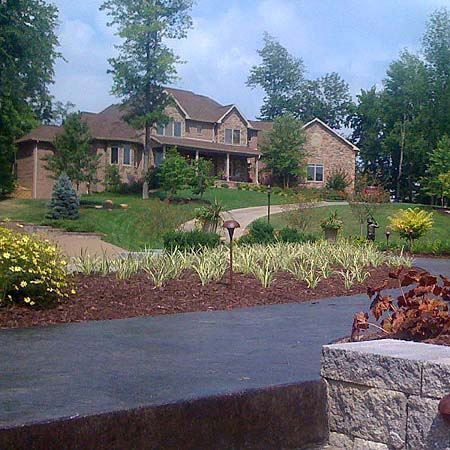 A large house sits on top of a lush green hillside