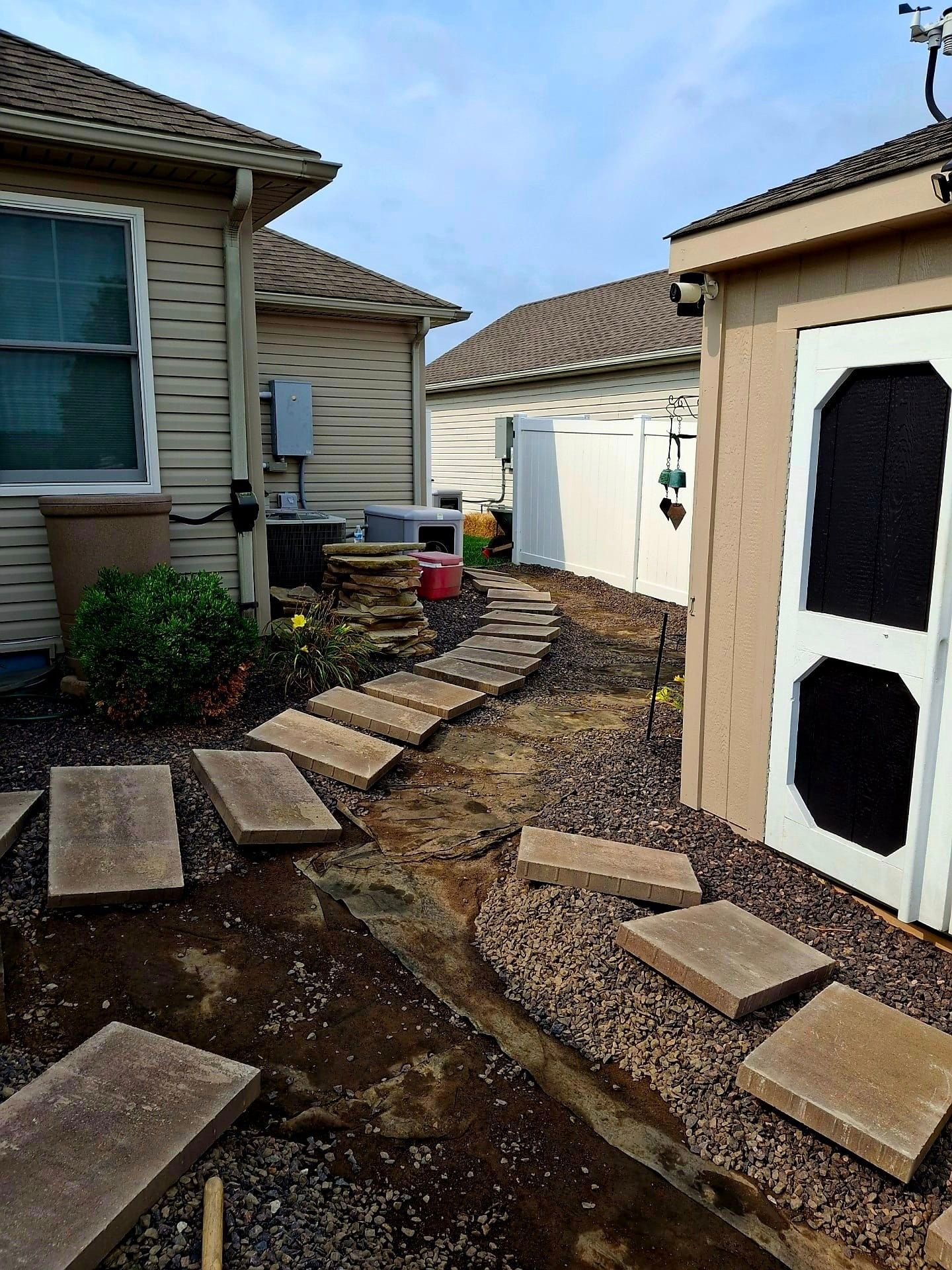 A shed with a screened in door is next to a house.