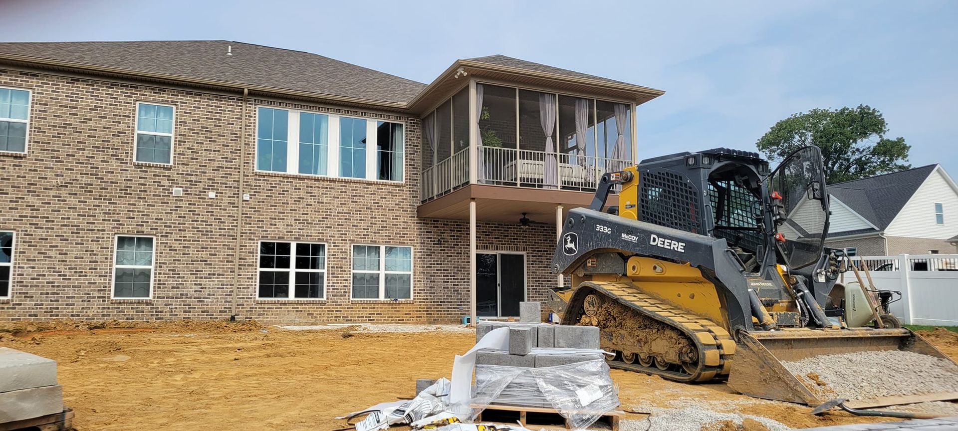 A large brick house is being built with a bulldozer in front of it.