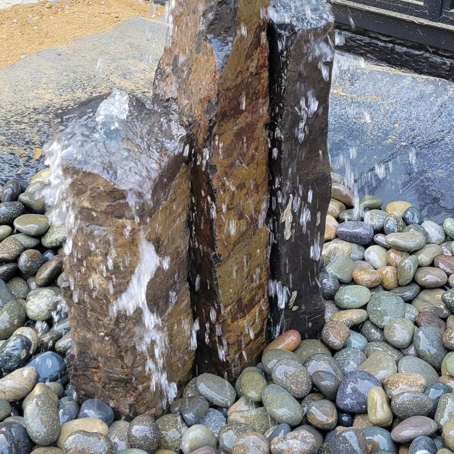 A fountain is surrounded by rocks and water is coming out of the rocks