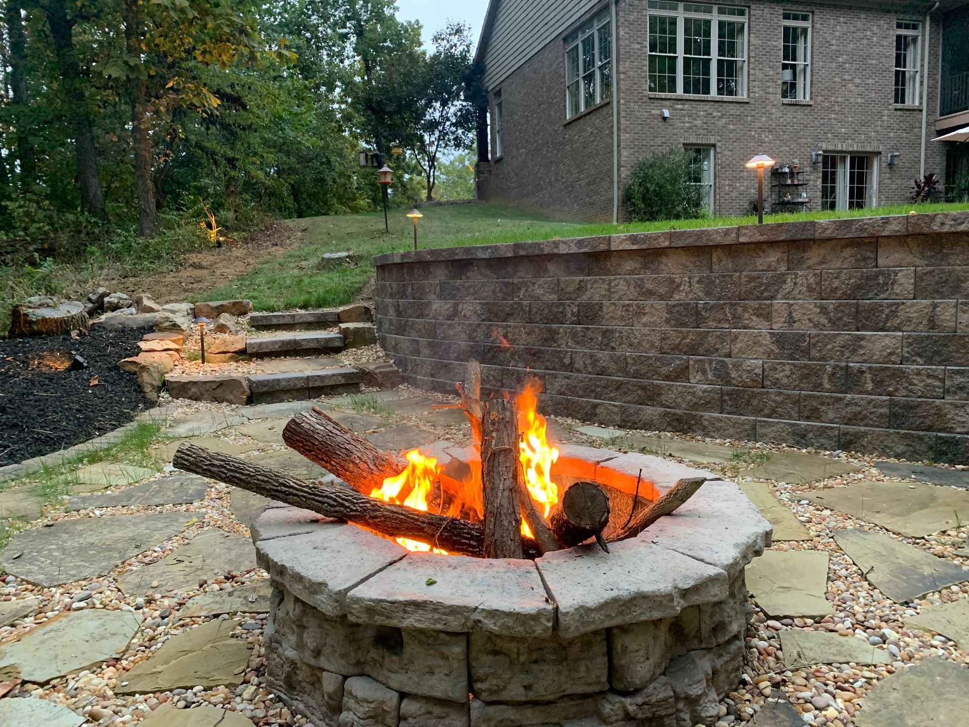 A fire pit is lit up in front of a house.