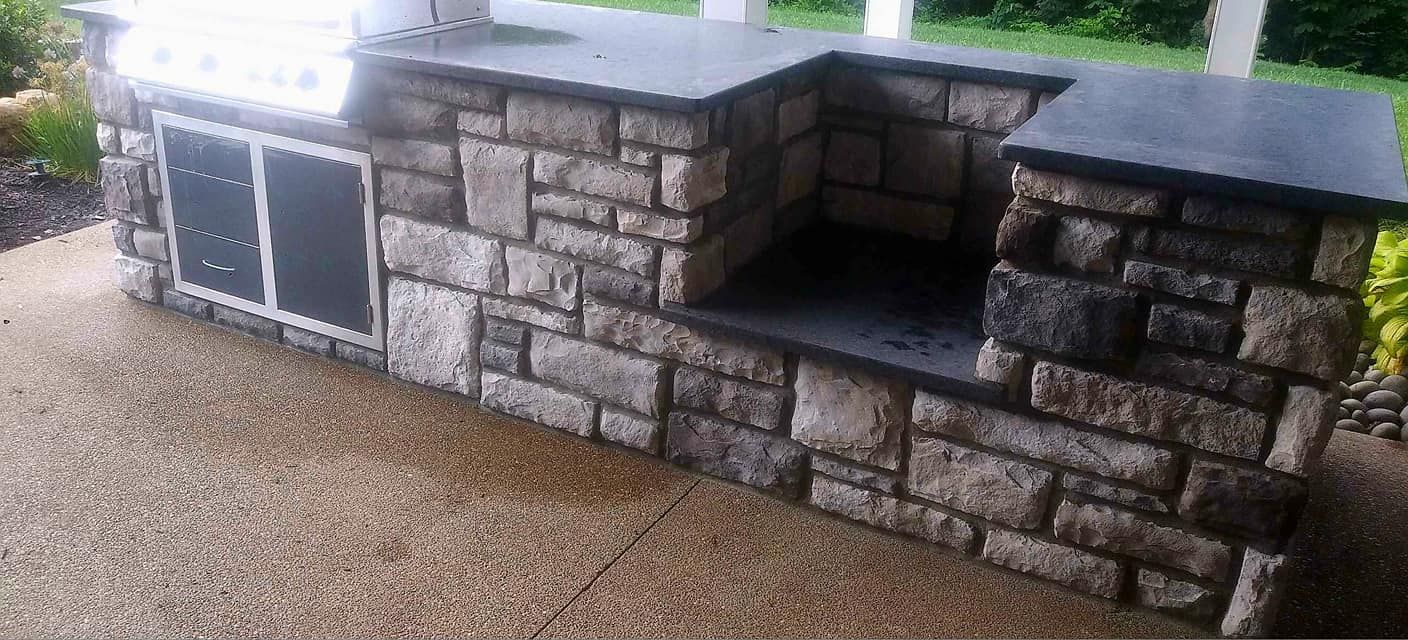 A stone wall with a grill on top of it.