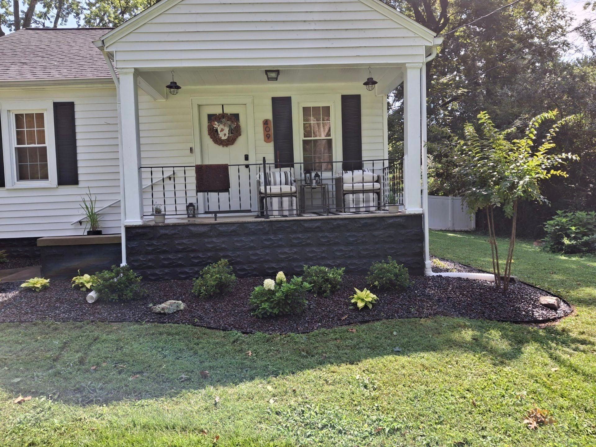 A white house with a porch and chairs on it.
